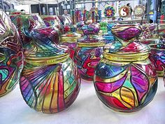 many colorful glass vases sitting on top of a white table covered in lots of different colors