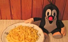 a stuffed animal sitting next to a plate of pasta