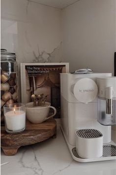 a coffee maker sitting on top of a counter next to a book and candle holder