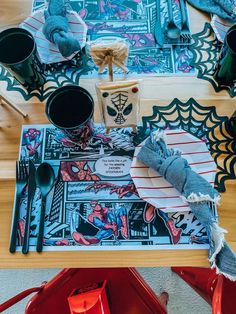 the table is decorated with spiderman napkins and place mats for halloween dinnerware