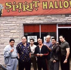 a group of people standing in front of a building with a car parked outside it