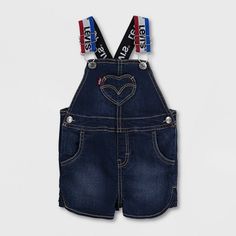 Stretch denim. Straight neck. 2 adjustable shoulder straps with buckle closure. Heart chest pocket. 2 side pockets. 2 back pockets. Ruffle at legs. Snap closures at waist. Snap tape closures along inseam for changing and dressing. Snap Tape, Denim Shortalls, American Workwear, Baby Size Chart, Heart Pocket, Stretch Denim Fabric, Girls Denim, Levi Shorts, Baby & Toddler Clothing