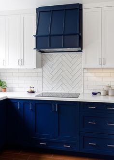 a kitchen with blue cabinets and white tile backsplashes on the countertops