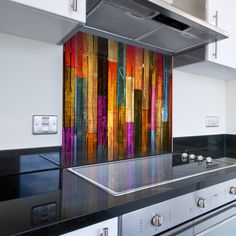 a kitchen with stainless steel appliances and colorful art on the backsplash above it