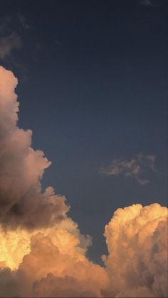 the plane is flying high in the sky with clouds behind it and an airplane on the ground below