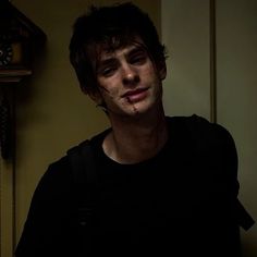 a young man with blood on his face standing in front of a wall and clock