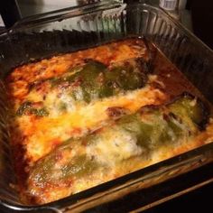 a casserole dish with cheese and green peppers in it sitting on the stove