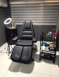 a black chair sitting on top of a white tile floor next to a hair dryer