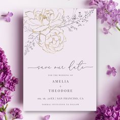 the wedding card is surrounded by purple flowers