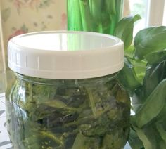 a jar filled with green vegetables sitting on top of a table