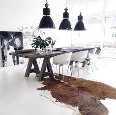 a dining room table and chairs with cow hide rug on the floor in front of it