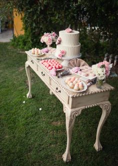 a table that has some cakes on it and flowers in the grass next to it