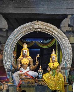 two statues of deities sitting in front of a mirror