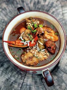 a close up of a bowl of soup with shrimp and other food items in it