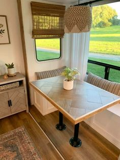 a table and chairs in front of a window with the view of an open field