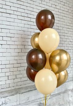 a bunch of balloons that are in front of a brick wall with white bricks on it