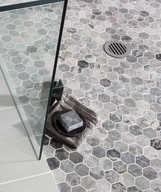 a bathroom with hexagonal tiles and a glass shower door that has a toilet in it