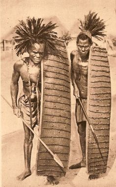 two native american men standing next to each other holding surfboards and paddles in their hands