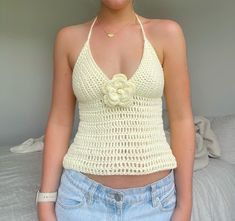 a woman wearing a white crochet top with a flower on the front and bottom