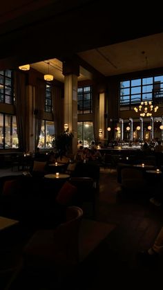 a dimly lit restaurant with large windows and chandeliers