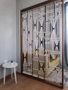 a room divider made out of rope and wood with white furniture in the background