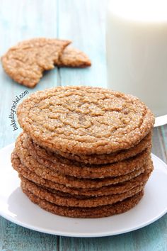 a stack of cookies sitting on top of a white plate next to a glass of milk