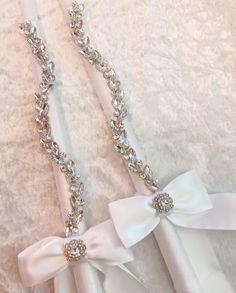 two wedding garters with white satin bows and crystal stones on them, tied together