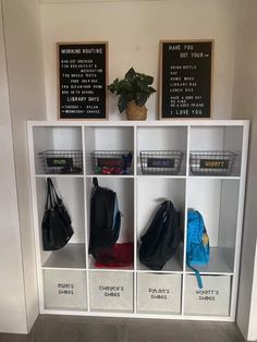 a white shelf filled with lots of bags and purses next to a wall mounted chalkboard