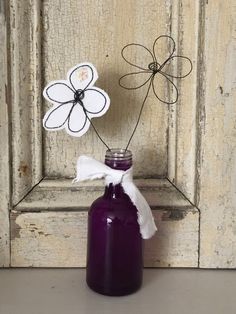 a purple vase with two flowers in it