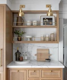 a kitchen with marble counter tops and wooden cabinets, gold accents on the upper shelves