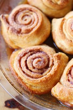 some cinnamon rolls are on a glass plate