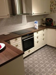 a kitchen with white cabinets and wood counter tops, an oven and dishwasher