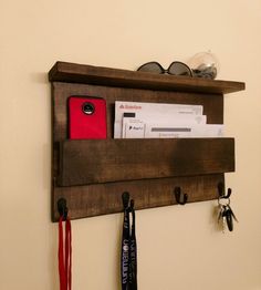 a wooden shelf with some keys and other items on it, hanging from the wall