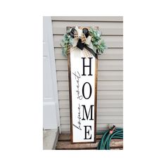 a wooden sign that says home with flowers on it and a ribbon hanging from the front