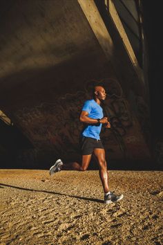 a man running in the dirt under a bridge