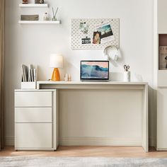 a white desk with a laptop on top of it next to a lamp and shelves