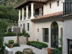 an outdoor courtyard with potted plants and steps leading up to the front of a house