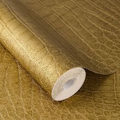 a roll of metallic foil on top of a gold leather textured table cloth with white tape