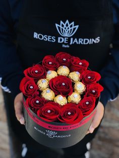 a person holding a box filled with chocolates and roses in it's hands