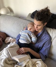 a woman holding a baby while reading a book