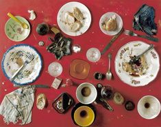 an assortment of dishes and utensils on a red table cloth covered in food