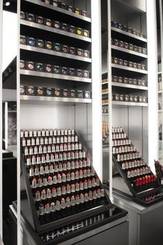 two shelves filled with lots of different types of bottles in a room that has metal shelving