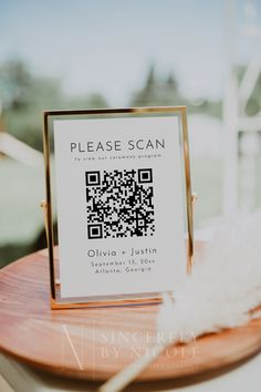 a wooden table topped with a qr code next to a white feather on top of it