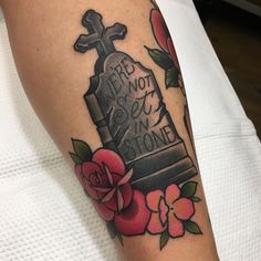 a tattoo on the arm of a person with a cross and roses around it,