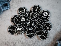 a pile of black and white zodiac buttons on a gray surface with blue rocks in the background