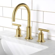 a gold faucet on a white sink in a bathroom