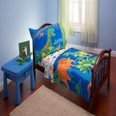 a child's bedroom with blue walls and wooden flooring is decorated in dinosaur themed bedding