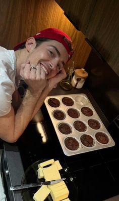 a man sitting in front of a pan filled with cupcakes and butter on top of a stove