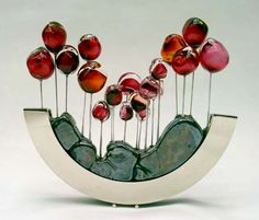 there is a sculpture made out of glass and metal with red balls on it's stems