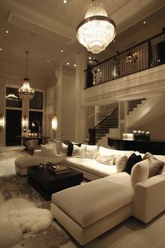 a living room filled with lots of furniture and a chandelier hanging from the ceiling